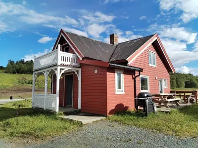 a red house with a porch and a picnic table at Sommerstue Hessdalen in Ålen