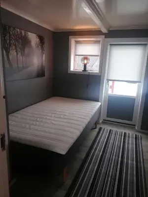 a bed in a room with two windows at Sommerstue Hessdalen in Ålen