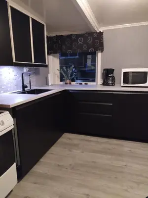 a kitchen with black cabinets and a sink and a microwave at Sommerstue Hessdalen in Ålen