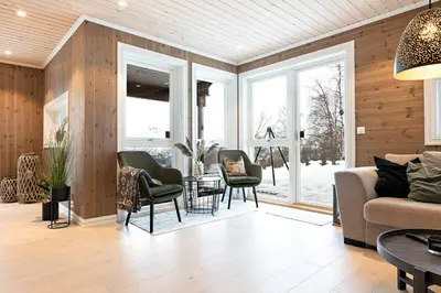 a living room with wooden walls and a couch and chairs at Lykkeli in Stranda