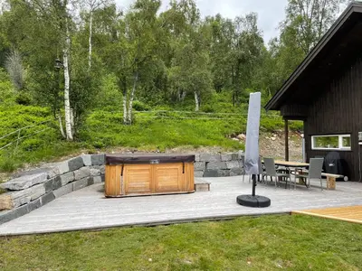a wooden building on a patio next to a stone wall at Lykkeli in Stranda