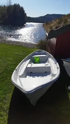 a white boat sitting on the grass near the water at Teigen Leirstad, feriehus og hytter in Eikefjord