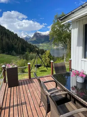 a deck with a table and chairs and a view of a mountain at Tunold Gård - Kårhus in Mindresunde
