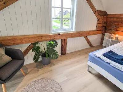 a bedroom with a bed and a chair and a window at 6 person holiday home in Bud in Bud