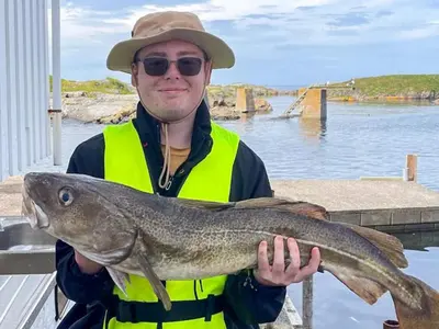 a man in a hat holding a fish at 6 person holiday home in Bud in Bud