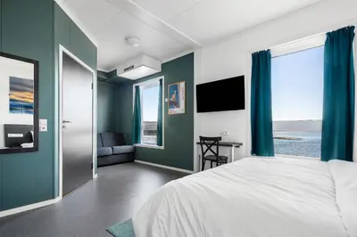 a bedroom with a large bed with blue walls at Aiden by Best Western Trondheim Airport in Stjoerdal