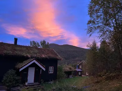 a house with a grass roof with a sunset in the background at Stille og fredelig med panoramautsikt in Valsøybotn