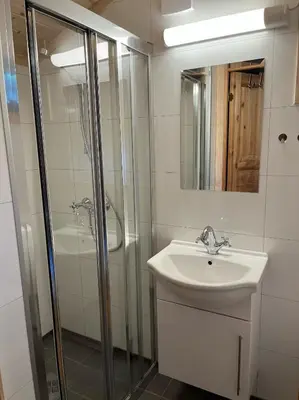 a white bathroom with a sink and a shower at Melkevoll Bretun Camping in Briksdalsbre