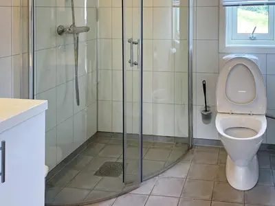 a bathroom with a toilet and a glass shower at 5 person holiday home in averøy in Stokke
