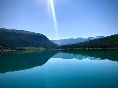 a view of a large lake with trees and mountains at Reinheimen Lodge in Skjåk