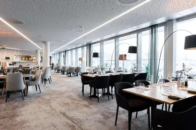 a dining room with tables and chairs and windows at Scandic Ørnen in Bergen