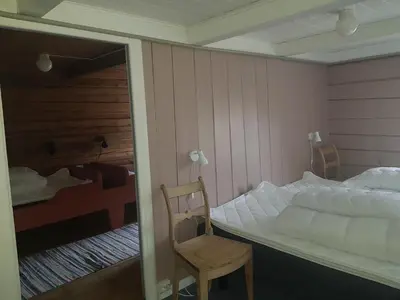 a bedroom with a bed and a chair and a mirror at Lensmansgarden Marteinsgarden in Innfjorden