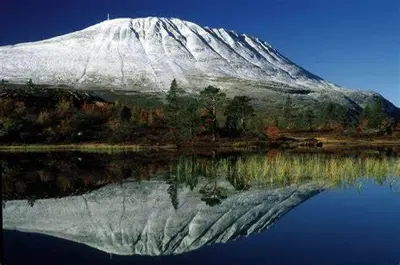 a snow covered mountain reflecting in the water at Bakka in Bakka