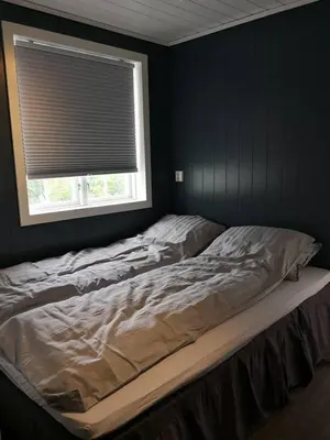 an unmade bed in a bedroom with a window at Yttervik gard in Steinkjer