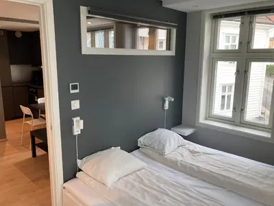 a bedroom with a bed and two windows and a mirror at Skansen Apartments in Bergen