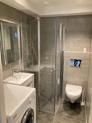 a bathroom with a shower and a toilet and a sink at Skansen Apartments in Bergen