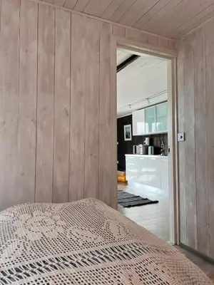 a bedroom with wooden walls and a bed and a kitchen at Høgli på Yttervik gard in Fosnesstranden