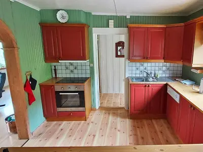 a small kitchen with red cabinets and a sink at 9 person holiday home in KORTGARDEN in Skalle