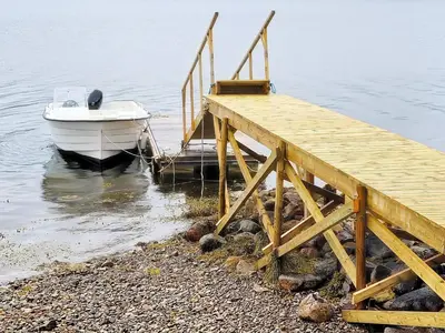 a boat is docked next to a wooden dock at 9 person holiday home in KORTGARDEN in Skalle