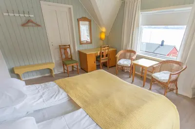 a bedroom with a bed and a table and chairs at Raaehuset in Lavik