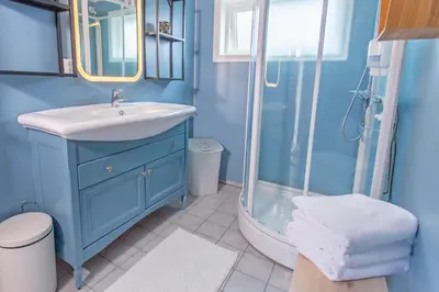a blue bathroom with a sink and a shower at Raaehuset in Lavik