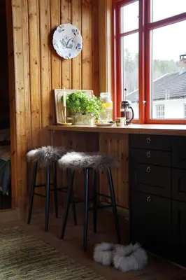 a kitchen with a counter with stools and a window at Bolkesjø Gaard in Notodden