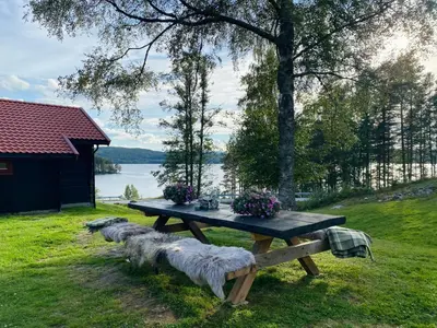 a picnic table in the grass next to a lake at Bolkesjø Gaard in Notodden