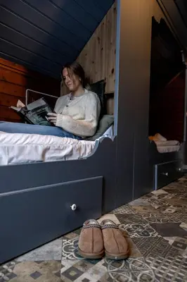 a woman sitting on a bed reading a book at Vollsnes Gjestehus in Stryn