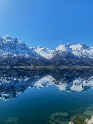 a reflection of snow covered mountains in a lake at Vollsnes Gjestehus in Stryn