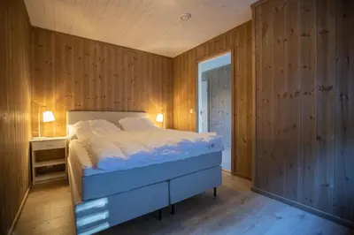 a bedroom with a bed and a wooden wall at Hodlekve Panorama 5 - amazing view in Sogndal