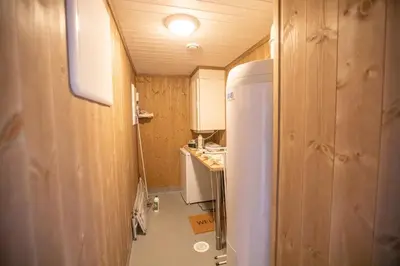 a small kitchen with a white refrigerator and wooden walls at Hodlekve Panorama 5 - amazing view in Sogndal