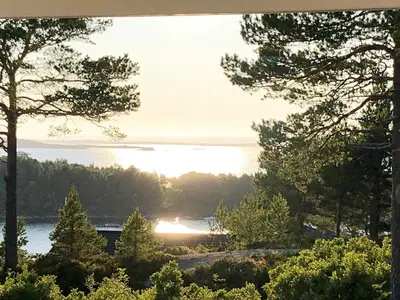 a view of a lake with the sun setting behind trees at 6 person holiday home in Aure-By Traum in Aure
