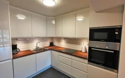 a kitchen with white cabinets and a sink and a microwave at Otnes Fjordside - Large 80m2 860sqft in Aurland