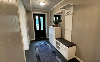 a hallway with a black door and a room with a rug at Otnes Fjordside - Large 80m2 860sqft in Aurland
