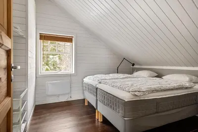 a bed in a white room with a window at Cabin in Trysil with seaview to lake in Trysil