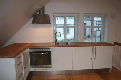 a kitchen with white cabinets and a sink and a window at Villa Skansen in Bergen