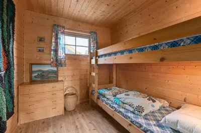 a bedroom with two bunk beds in a log cabin at Cabin alongside the beautiful fjærlandsfjord in Fjarland