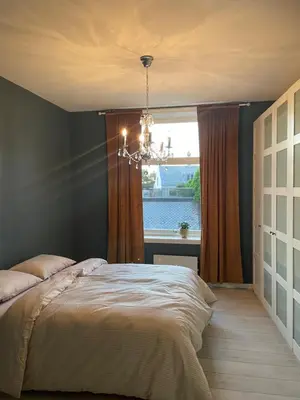 a bedroom with a bed with a window and a chandelier at City Center Apartment in Ålesund