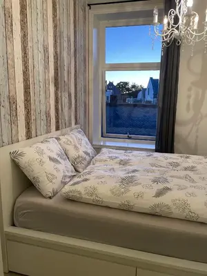 a bed with two pillows and a window at City Center Apartment in Ålesund