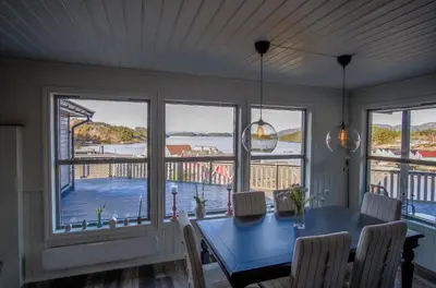 a dining room with a blue table and views of the water at Exclusive fjordside villa with swimming pool, sauna, jacuzzi and boat hire in Sveio