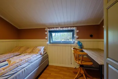 a bedroom with a bed and a desk and a window at Exclusive fjordside villa with swimming pool, sauna, jacuzzi and boat hire in Sveio