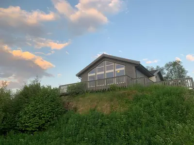 a house on top of a grassy hill at Exclusive fjordside villa with swimming pool, sauna, jacuzzi and boat hire in Sveio