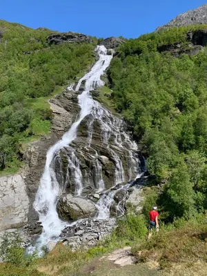 a man standing in front of a waterfall at Dispen feriehus in Stryn