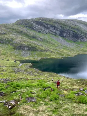 a group of people walking on a hill near a lake at Dispen feriehus in Stryn