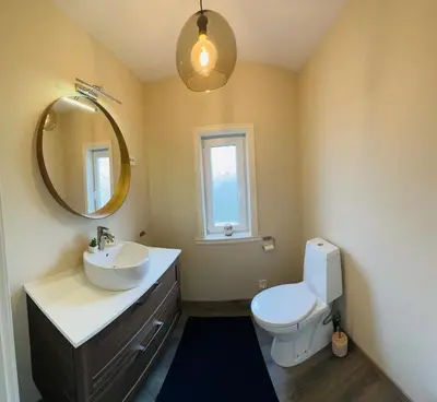 a bathroom with a sink and a toilet and a mirror at Feriehus med badestamp in Lavik