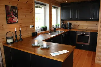 a kitchen with black cabinets and a wooden counter top at Storemyr by Norgesbooking - cabin with amazing view in Hol