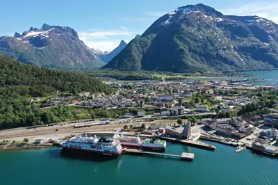a cruise ship docked at a dock in the mountains at Åndalsnes Sentrum 1-room Apartment in Åndalsnes