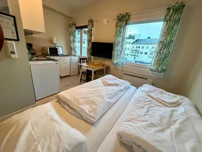 two beds in a room with a kitchen and a window at Åndalsnes Sentrum 1-room Apartment in Åndalsnes