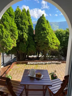 a table on a patio with a view of trees at Sukkertoppen Apartment in Ålesund