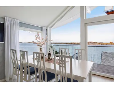 a dining room with a table and chairs with a view of the water at Atlantic Panorama in Vevang